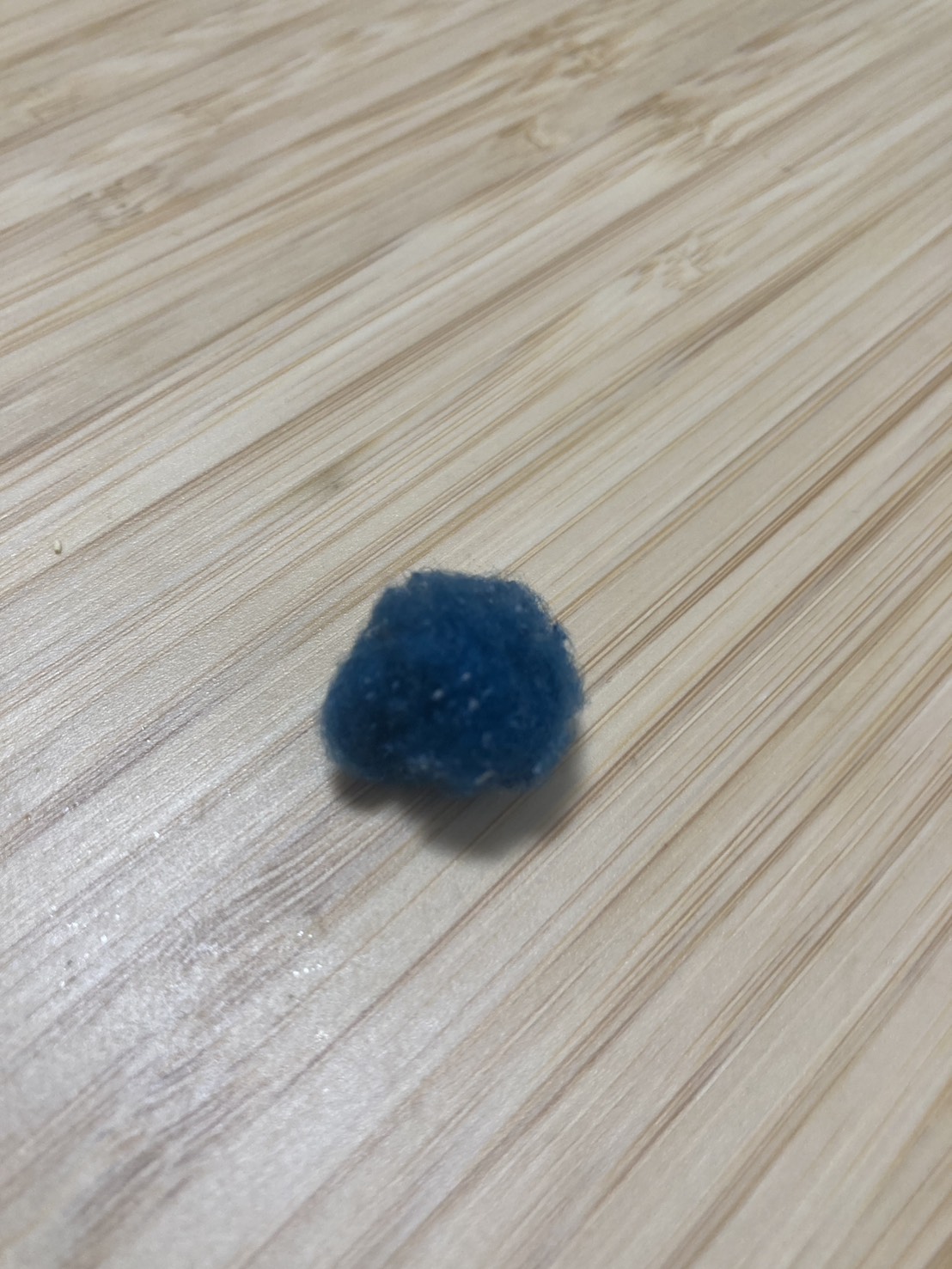 木目のテーブルの上に置いた、手でむしり取った毛玉のかたまり